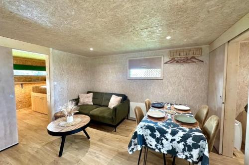 ein Wohnzimmer mit einem Tisch und einem Sofa in der Unterkunft Les 1000 Ailes-Expérience Unique dans une Hutte in Le Crotoy