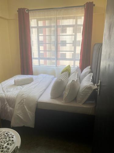 基苏木Makasembo Estate的窗户前的一张带白色枕头的床