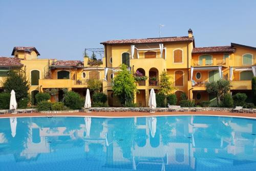 a hotel with a swimming pool in front of a building at Borgo del Torchio H3 ByBookinggardalake in Manerba del Garda