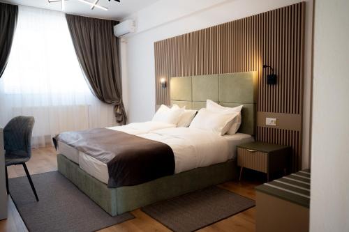 a bedroom with a large bed and a chair at Hotel Dumbrava in Rupea