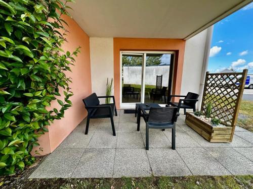 a patio with chairs and a table in front of a house at Appartement neuf proche Guingamp in Ploumagoar
