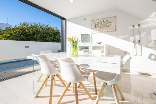 a white dining room with a glass table and white chairs at Villa Lux - Golden Nelly By Algartur in Luz de Tavira