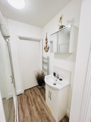 a white bathroom with a sink and a mirror at Southside Street Apartments in Plymouth