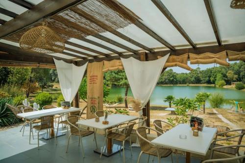 a patio with tables and chairs and a view of a lake at ZEcamping 3 étoiles vue lac environnement calme in Douville