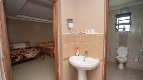 ein Badezimmer mit Waschbecken und Toilette und ein Bett in der Unterkunft Private home near JKIA Airport in Nairobi