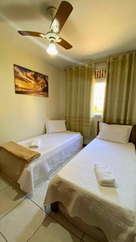 a bedroom with two beds and a ceiling fan at Excelente Apartamento Climatizado em Jacaraipe in Serra
