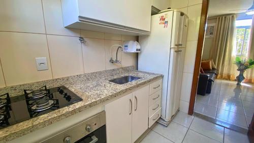 uma cozinha com um lavatório, um fogão e um frigorífico em Excelente Apartamento Climatizado em Jacaraipe em Serra