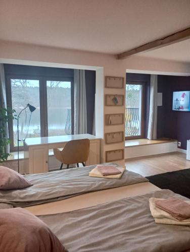 Un dormitorio con dos camas y un escritorio y ventanas. en Mrągowo Pokoje Apartament, en Mrągowo