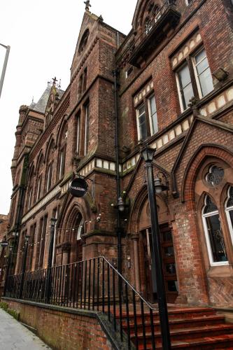 an old brick building with a black fence in front of it at Malacuna Liverpool in Liverpool