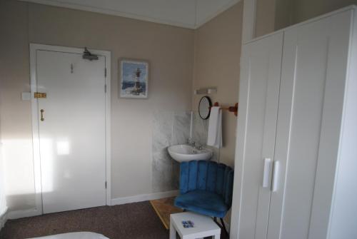 Un baño con un lavabo y una silla azul. en The Curraghmore, en Shanklin