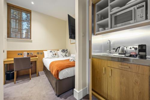 a bedroom with a bed and a kitchen with a sink at Kula London - Kensington in London