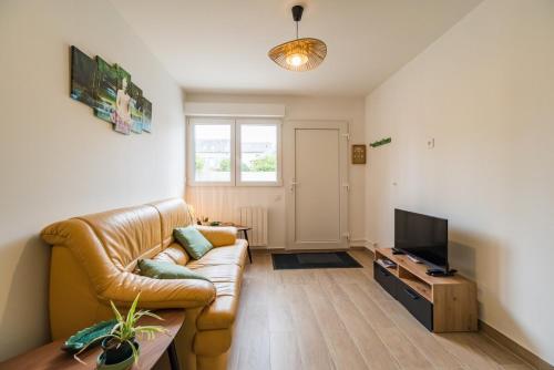 a living room with a leather couch and a television at Le T2 Zen de Guingamp confort au coeur de la ville in Guingamp