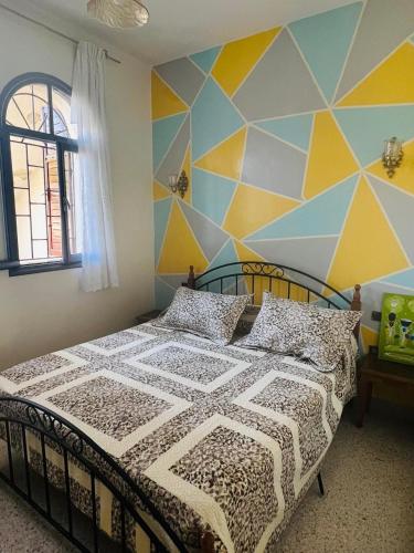 ein Schlafzimmer mit einem Bett mit einer geometrischen Wand in der Unterkunft Lala Khnata in Temara