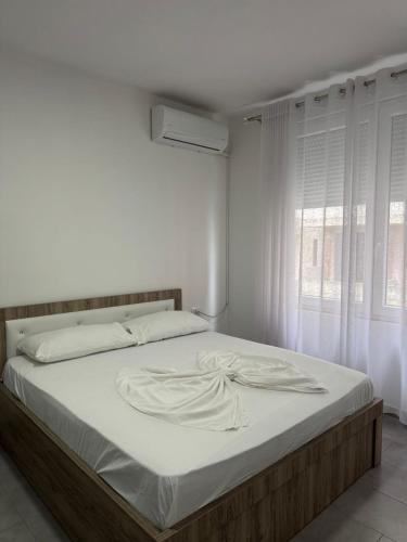 Un dormitorio con una cama con sábanas blancas y una ventana. en Shengjin apartaments leon, en Shëngjin