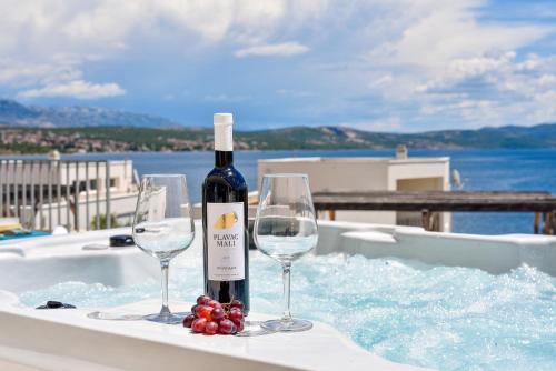 una bottiglia di vino e due bicchieri di vino in una vasca di Villa Costabella with heated pool a Posedarje (Possedaria)