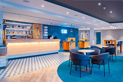 a restaurant with tables and chairs and a bar at Holiday Inn Express St. Albans - M25, Jct.22 in St. Albans