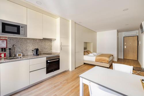 a kitchen with white cabinets and a room with a bed at Stay In Vila Real Apartments in Vila Real