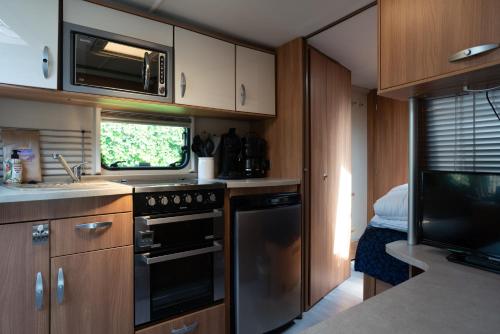Oosterendglamping luxe caravan的厨房配有炉灶、水槽和微波炉