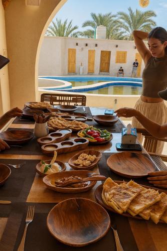 Una mujer parada en una mesa con platos de comida. en Asfay Lodge Siwa, en Siwa