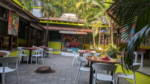 a restaurant with tables and chairs in a courtyard at Jungle Hostel by Mango Tree in Vagator