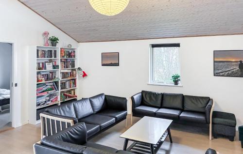 a living room with black leather furniture and a book shelf at Beautiful Home In Rødby With Wifi in Tjørnebjerg
