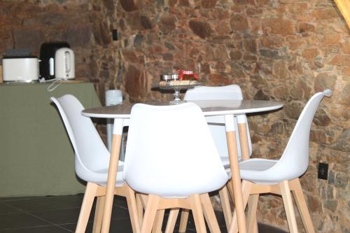 a table with four white chairs around it at Linhares - Country House Turismo, Natureza e Aventura in Castanheira de Pêra