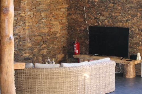 a living room with a television and a wicker chair at Linhares - Country House Turismo, Natureza e Aventura in Castanheira de Pêra