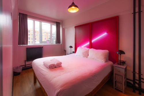 a bedroom with a large white bed with a pink headboard at Malacuna Liverpool in Liverpool