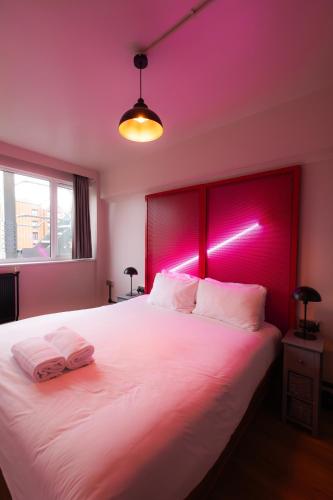 a bedroom with a large white bed with pink lighting at Malacuna Liverpool in Liverpool