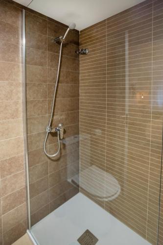 a shower with a glass door with a toilet at Habitaciones Algodón con baño propio in Palencia
