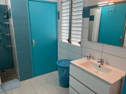 ein Badezimmer mit einem Waschbecken und einer blauen Tür in der Unterkunft Charmante maison avec vue sur mer - Plage à 1mn à pieds in Saint-Louis