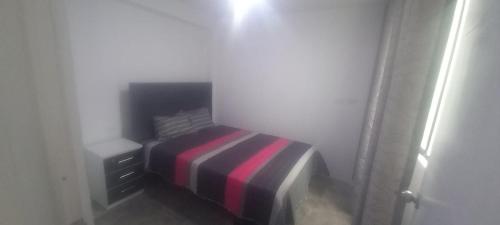 a small bedroom with a bed with a striped blanket at Hospedaje C y A in Lima