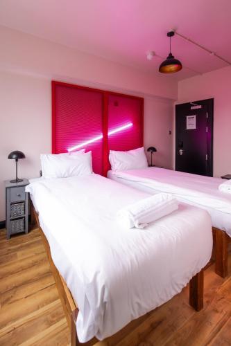 two beds in a room with pink lighting at Malacuna Liverpool in Liverpool