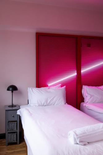 two beds in a room with a pink headboard at Malacuna Liverpool in Liverpool