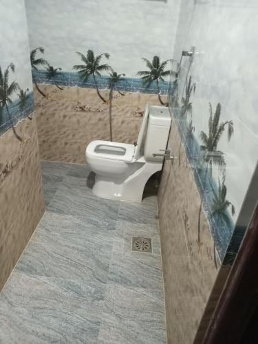 a bathroom with a toilet with palm trees on the wall at Galle Paradise Inn in Galle