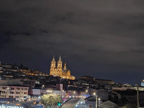 a city lit up at night with a building at Hostal Marín Central - Quito in Quito