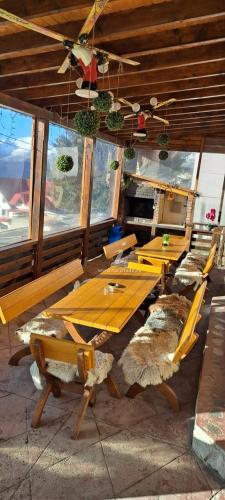 a group of wooden tables and chairs in a room at Pensiunea MariFlor in Ranca