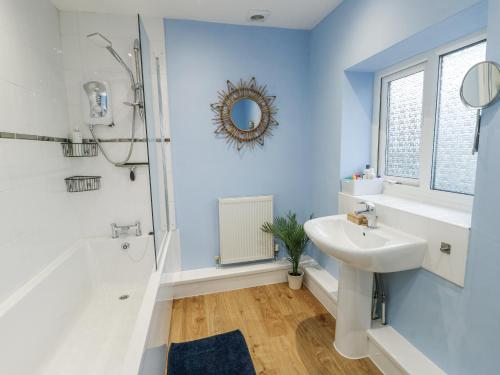 a bathroom with a white sink and a shower at Hafan Hapus in Beaumaris