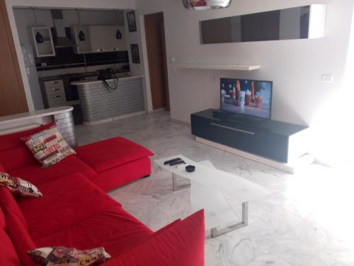 a living room with a red couch and a tv at Appartement les jardins de Carthage in Carthage
