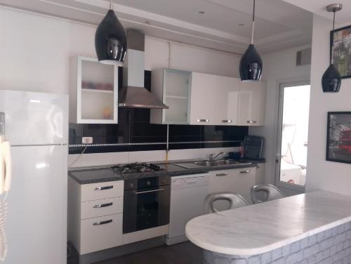 a kitchen with white cabinets and a white refrigerator at Appartement les jardins de Carthage in Carthage