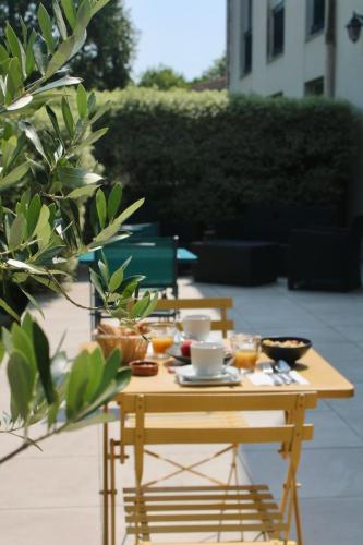 Una mesa de madera con comida y bebidas encima. en Hôtel de la Marine, en Saint-Herblain