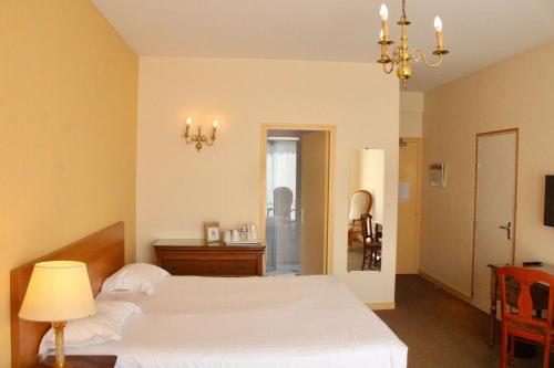 Un dormitorio con una cama, una mesa y una lámpara de araña. en Hôtel de la Marine, en Saint-Herblain