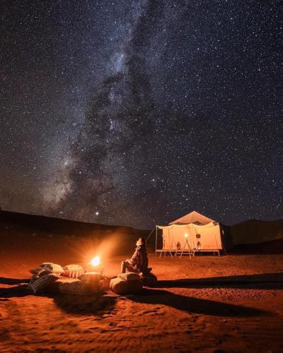 梅尔祖卡Memorable Starry Camp的坐在帐篷前的星空下的人