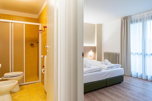 a bedroom with a bed and a bathroom with a shower at Hotel Bella Italia Piancavallo in Piancavallo