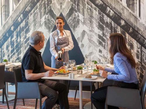 tres personas sentadas en una mesa en un restaurante en Hotel Mercure Lisboa, en Lisboa