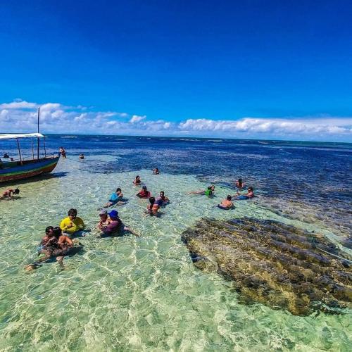 a group of people in the water near a boat at Casa Amaré - Moreré in Moreré