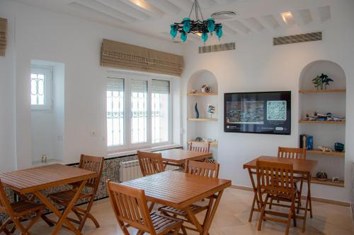 马赫迪耶Hôtel Al Jazira Mahdia的配有桌椅和电视的餐厅