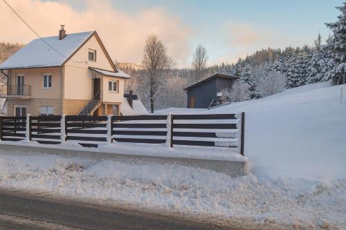 ein mit Schnee bedeckter Zaun neben einem Haus in der Unterkunft Valdora - Forest Oasis 
