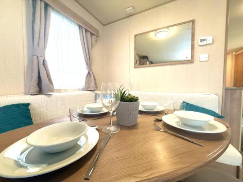 een houten tafel met borden, kommen en wijnglazen bij Paddy's Place in Filey