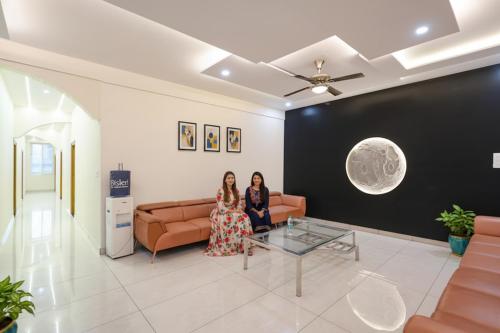 Dos mujeres sentadas en un sofá en una sala de estar en FabHotel Ayodhya Palace, en Bangalore